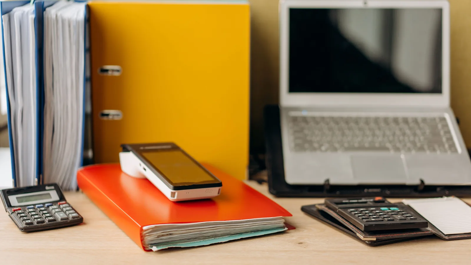 Organized desk with a laptop, calculators, folders, and financial documents
