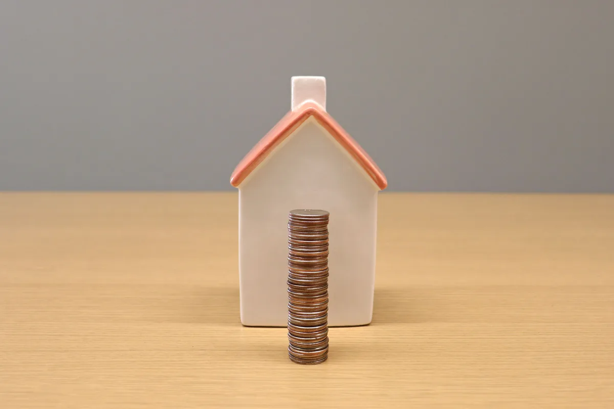 Small house model with a stack of coins in front